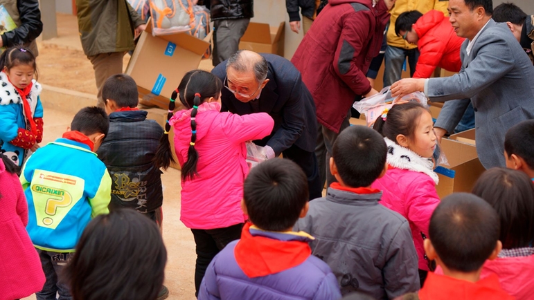 副总经理王卓军教授为孩子们发放书包和文具